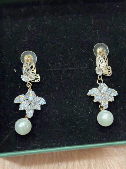 Pair of earrings with floral designs and pearls on a black background